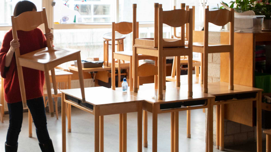 Juf zet stoelen op de tafel