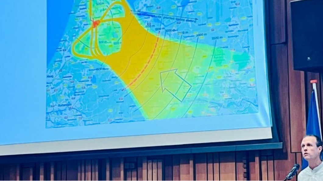 Grote presentatie met gekleurde zone boven midden Nederland. Daarvoor een jongeman achter een microfoon