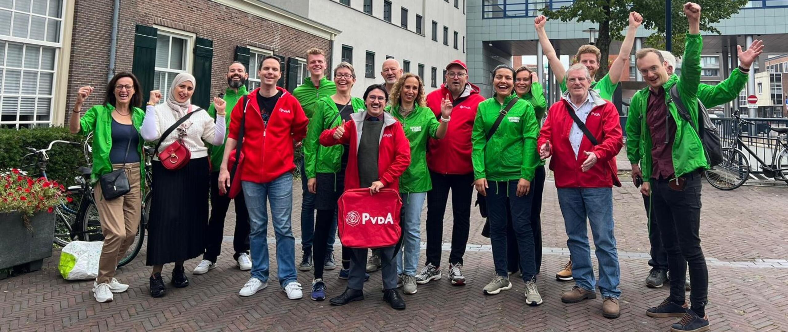 Grote groep blije mensen met groene en rode jasjes aan