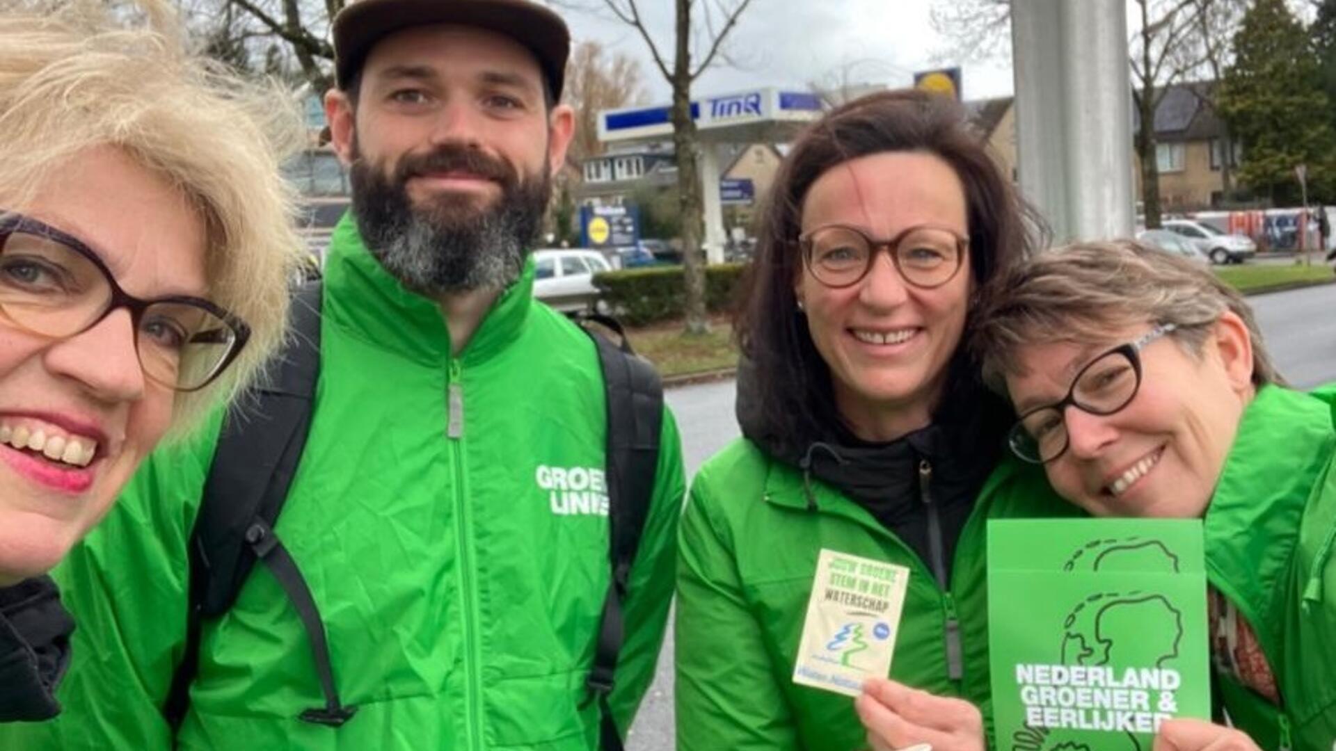 Lachende mensen met groene jasjes en flyer